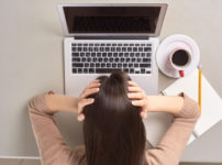 パソコンの前で頭を抱える女性